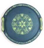 Round navy wooden tray with gold handles and symmetrical golden mandala design.