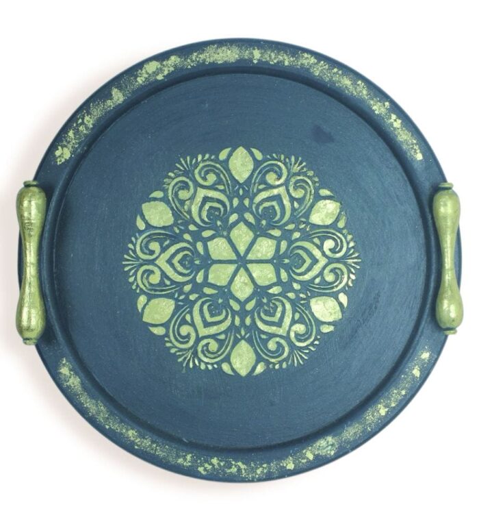 Round navy wooden tray with gold handles and symmetrical golden mandala design.