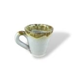 Purity Heritage handmade ceramic mug with white glaze and golden drip effect.