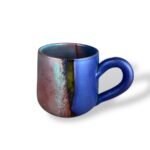 Ceramic mug with an artistic blend of earthy red, vibrant turquoise, and deep blue tones, featuring a matte and glossy finish.