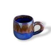 Handcrafted ceramic mug with matte blue base and flowing sand-brown glaze, inspired by river landscapes.