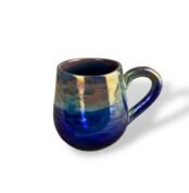 Glossy ceramic mug with a reflective gold and deep blue glaze, highlighting elegant curves and radiant finish.