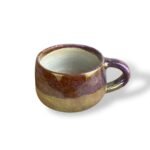 Handcrafted ceramic mug with a rich, warm purple and golden finish, showcasing royal elegance.