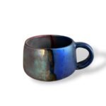 Handcrafted ceramic mug with a striking blue and iridescent finish, reflecting ancient craftsmanship.
