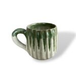 White and green ceramic mug with textured design and a curved handle, placed on a white background.