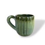 Green ceramic mug with a textured design and a curved handle, placed on a white background.