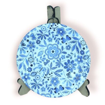 Round blue floral coaster displayed on a stand, featuring intricate flower and leaf patterns.