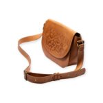 Angled view of brown small crossbody leather bag with Arabic calligraphy engraving and adjustable strap.