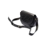 Angled view of black small crossbody leather bag with Arabic calligraphy engraving and adjustable strap.