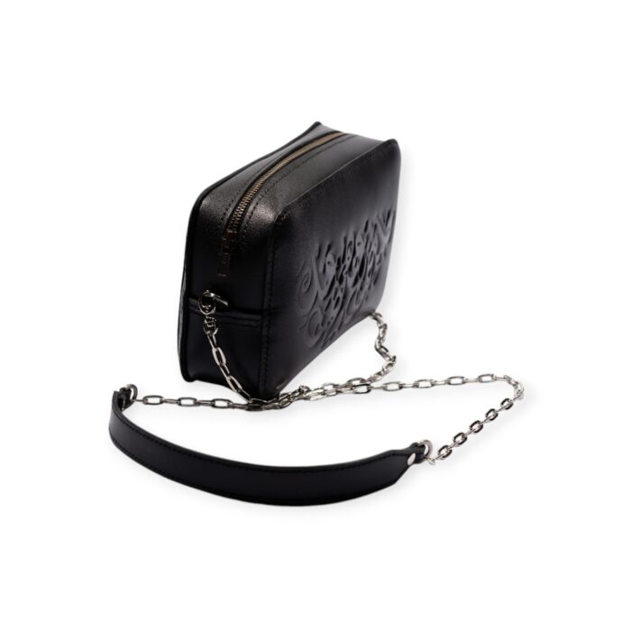 Side view of black leather rectangle crossbody bag with embossed Arabic calligraphy and silver chain strap.