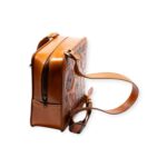 Side profile of brown leather square cross bag with embossed front design.