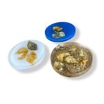 Set of round resin coasters with embedded dried flowers in white, blue, and amber-toned backgrounds.