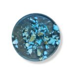 Top view of a round resin coaster with embedded seashells and crushed turquoise stones.