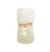 Rolled soft-textured blanket in off-white and pale green tones, tied with a burlap strap and branded tag
