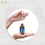 CairoCharm Hair Oil bottle with dropper, held in hand, showcasing the product.