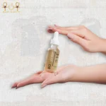 Hydra & Glow B5 serum with hyaluronic acid in a frosted glass dropper bottle, held between two hands on textured background.