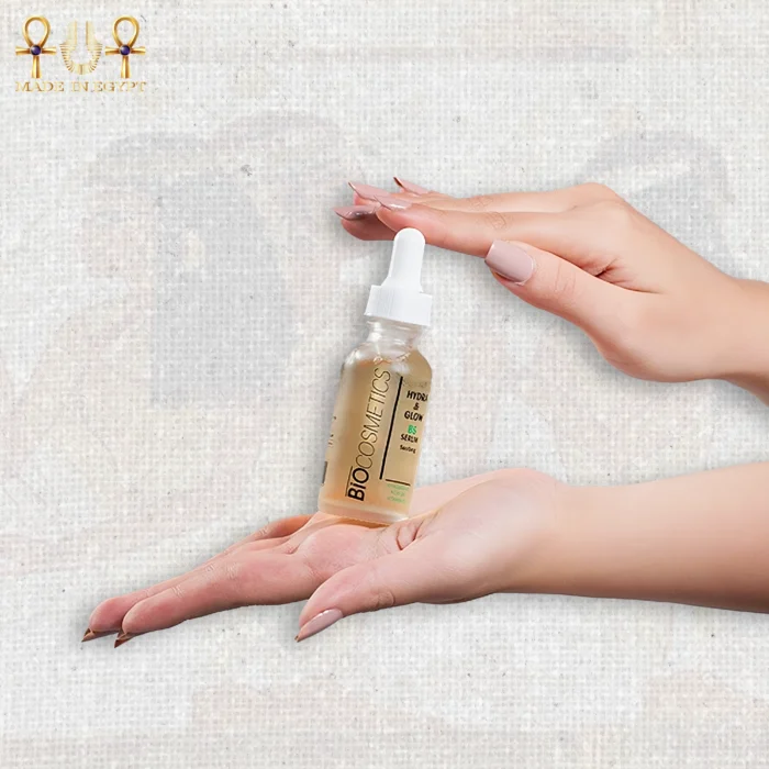 Hydra & Glow B5 serum with hyaluronic acid in a frosted glass dropper bottle, held between two hands on textured background.