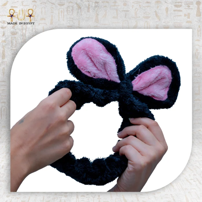 Two hands stretching the black Bunny Clasp with pink inner ears against a white background