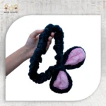 Hand holding black Bunny Clasp with pink inner ears on a white background