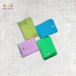 A stack of four Deep Exfoliating Towels in vibrant pastel colors – pink, yellow, blue, and green.