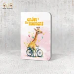 Enjoy the Moment notebook with a watercolor giraffe riding a bicycle and pastel balloons.