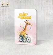 Enjoy the Moment notebook with a watercolor giraffe riding a bicycle and pastel balloons.