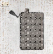 Handwoven Luxury Surprise clutch featuring delicate black and white beaded floral patterns with a tassel zipper closure.