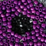Close-up of Mysterious Gaze bag showing purple beads and black crystal embroidery forming the eye design.