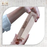 Hand holding Natural Wooden Comb engraved with BlackCat logo.