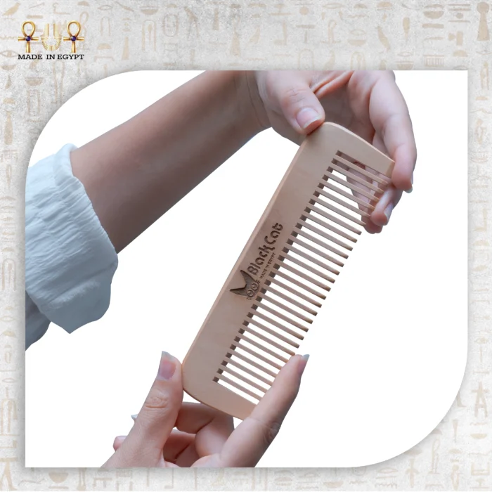 Hand holding Natural Wooden Comb engraved with BlackCat logo.