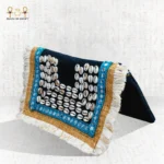 Side view of the Nubian Pearl bag with natural shells, turquoise embroidery, golden borders, and white fringes.
