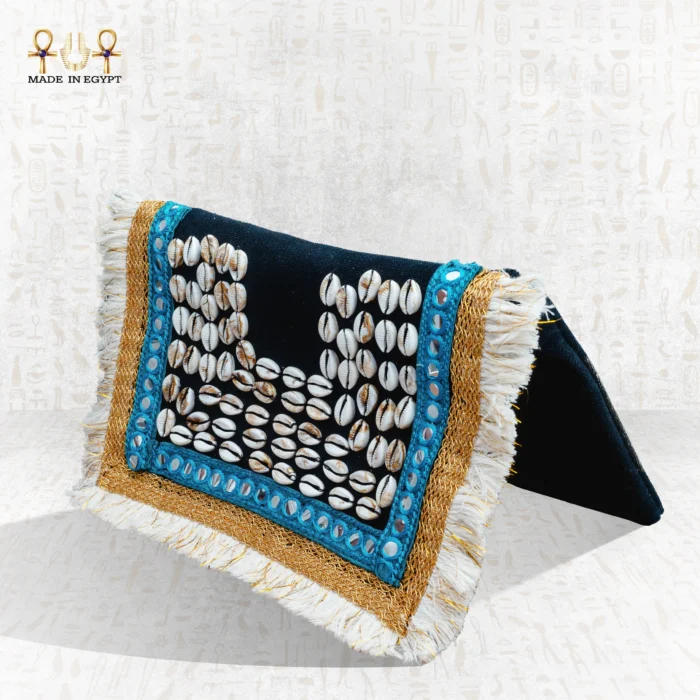 Side view of the Nubian Pearl bag with natural shells, turquoise embroidery, golden borders, and white fringes.