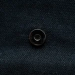 Close-up of the Pharaoh’s Touch bag showing silver magnetic button clasp on black fabric.