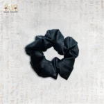 Close-up of a luxurious black silk hair tie on a white background.