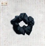 Close-up of a luxurious black silk hair tie on a white background.