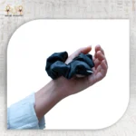 Silk black hair tie held in a hand, perfect for elegant hairstyles.