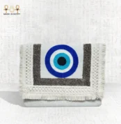 Front view of the Guardian Eye clutch featuring bold blue evil eye embroidery with textured silver and cream fringes.