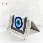 Side view of the Guardian Eye bag with blue evil eye embroidery, silver-thread borders, and cream fringe details.