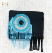 Front view of the Turquoise Eye clutch bag, showing circular turquoise, silver, and black bead embroidery with flowing blue and black fringes.