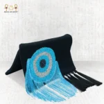 Side view of the Turquoise Eye clutch bag, featuring blue, silver, and black beaded evil eye embroidery with long turquoise and black fringes.