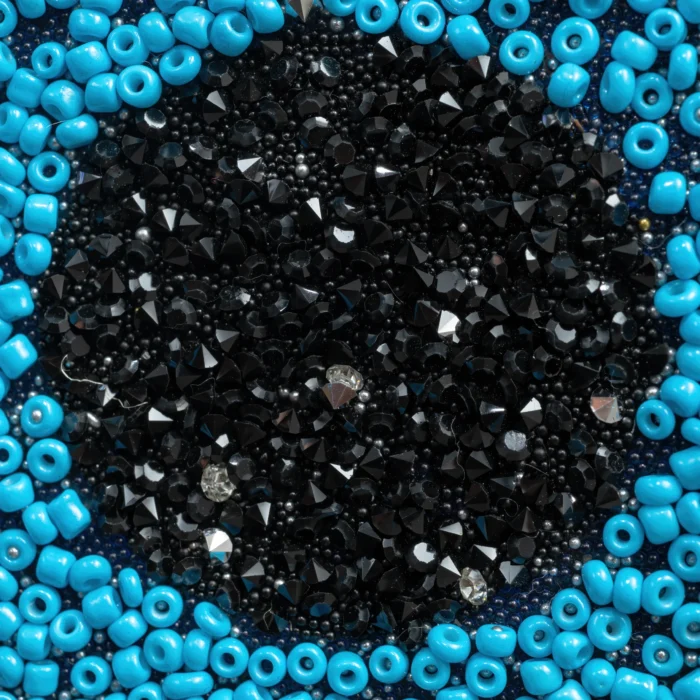 Turquoise Eye clutch with handcrafted blue, black, and silver bead embroidery forming a protective eye motif.