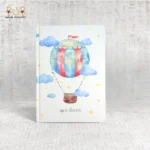 Whimsical hot air balloon notebook with red and blue stripes, clouds, and stars, titled "Up in the Air".