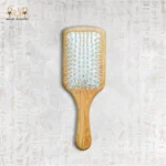 Wooden paddle hair brush with natural bristles on neutral background.