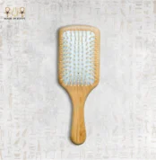Wooden paddle hair brush with natural bristles on neutral background.