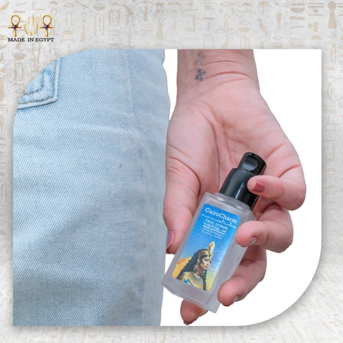 Close-up of hand holding CairoCharm Face Serum, showing its sleek design.