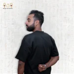 Close-up side back view of a man wearing a black Skyline Tee, hands behind his back, focusing on the upper body details.